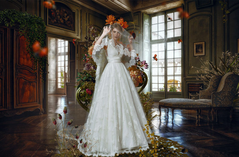 Fine art image of a model wearing a white dress in a luxury room surrounded by flowers
