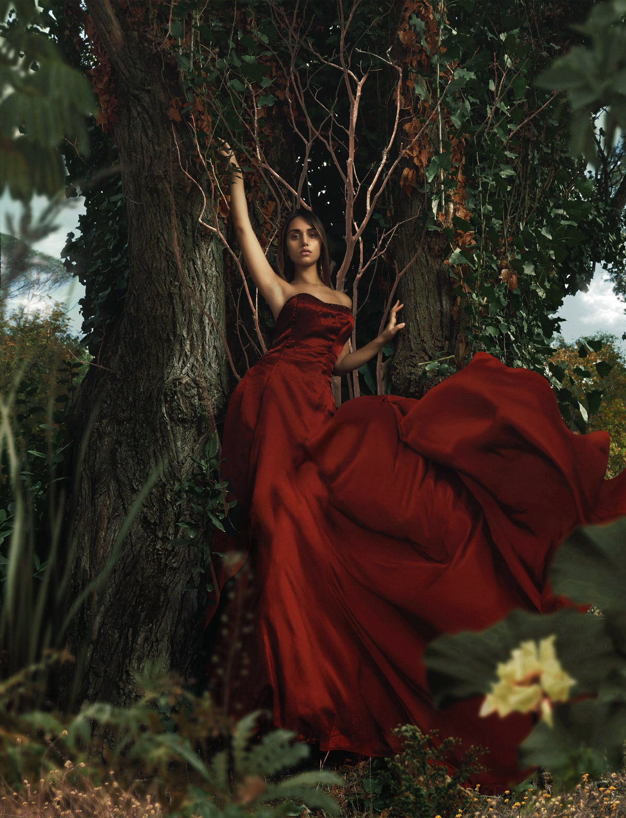 Painterly image of a model wearing a red dress surrounded by nature 